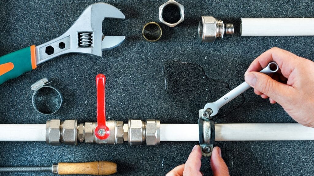 Plumber repairing a pipe valve with an adjustable wrench in Winter Park