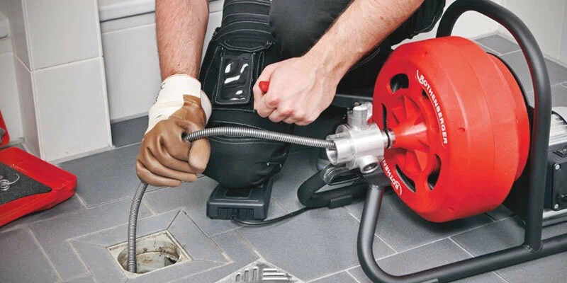 Plumber using a drain-cleaning machine in Winter Park