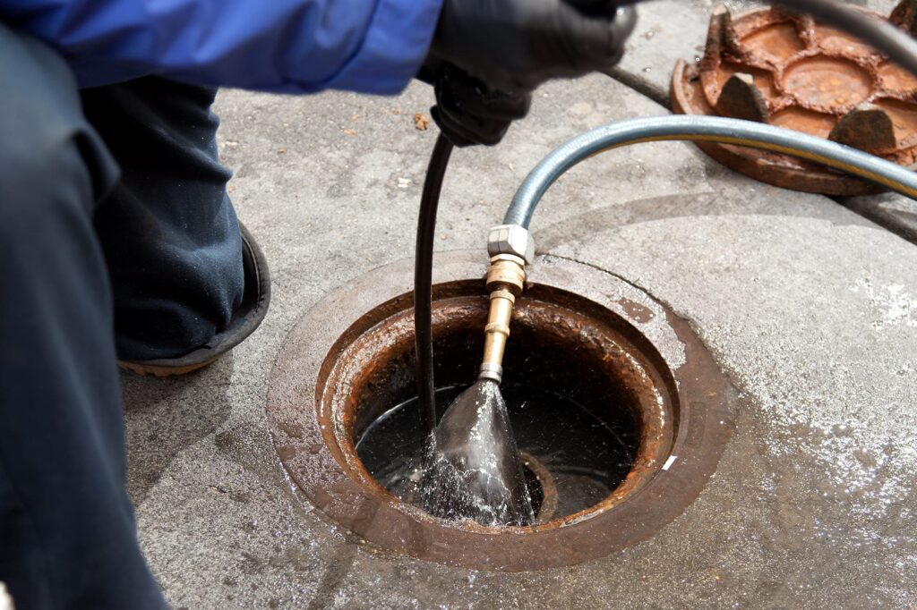 Plumber hydro jetting a sewer line through a manhole in Winter Park