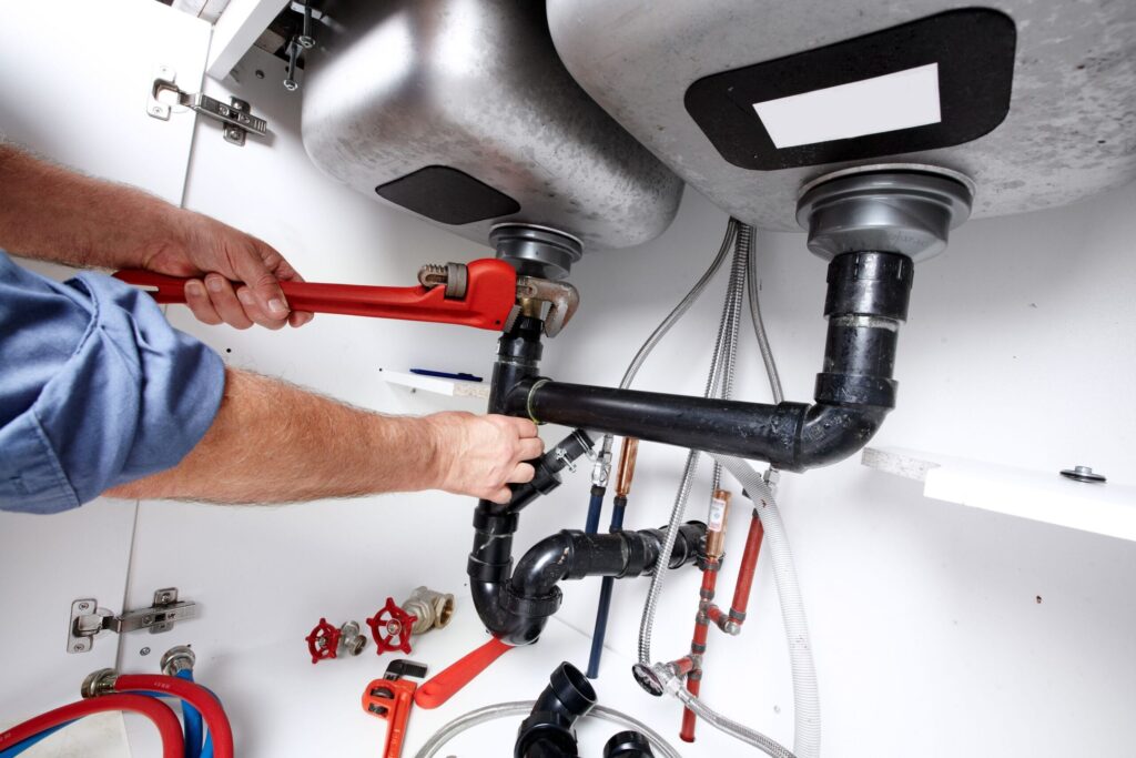 Plumber repairing drain pipes beneath a kitchen sink in Winter Park