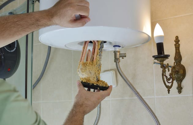 Technician removing mineral buildup from a water heater in Winter Park