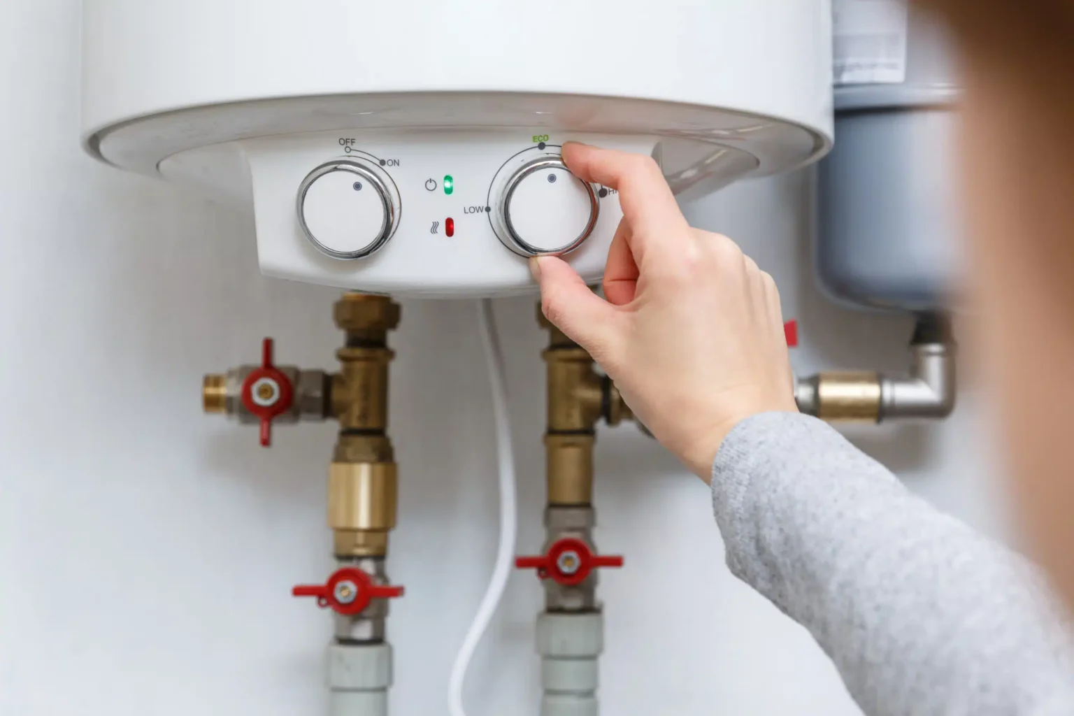 Homeowner adjusting the temperature controls on a water heater in Winter Park